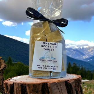 White Chocolate and Cardamom flavoured Homemade Scottish Tablet sitting on a tree stump with mountain views and blue sky